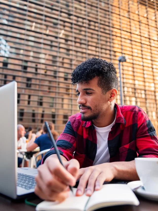 vertical-photo-young-latin-man-studying-with-his-computer-taking-notes-terrace-coffee-shop-city-concept-technology-urban-lifestyle